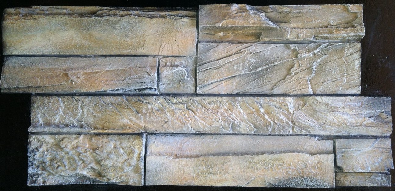A concrete stacked stone backsplash panel coloured in warm gold, tan and cream, photographed against a black background.