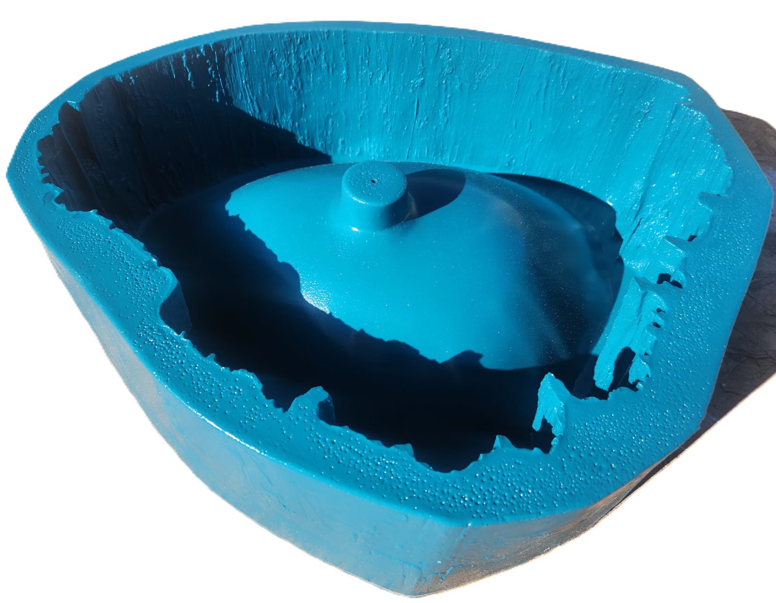 Looking into a blue silicone sink mold with an irregular cast rim and the drain boss at the centre.